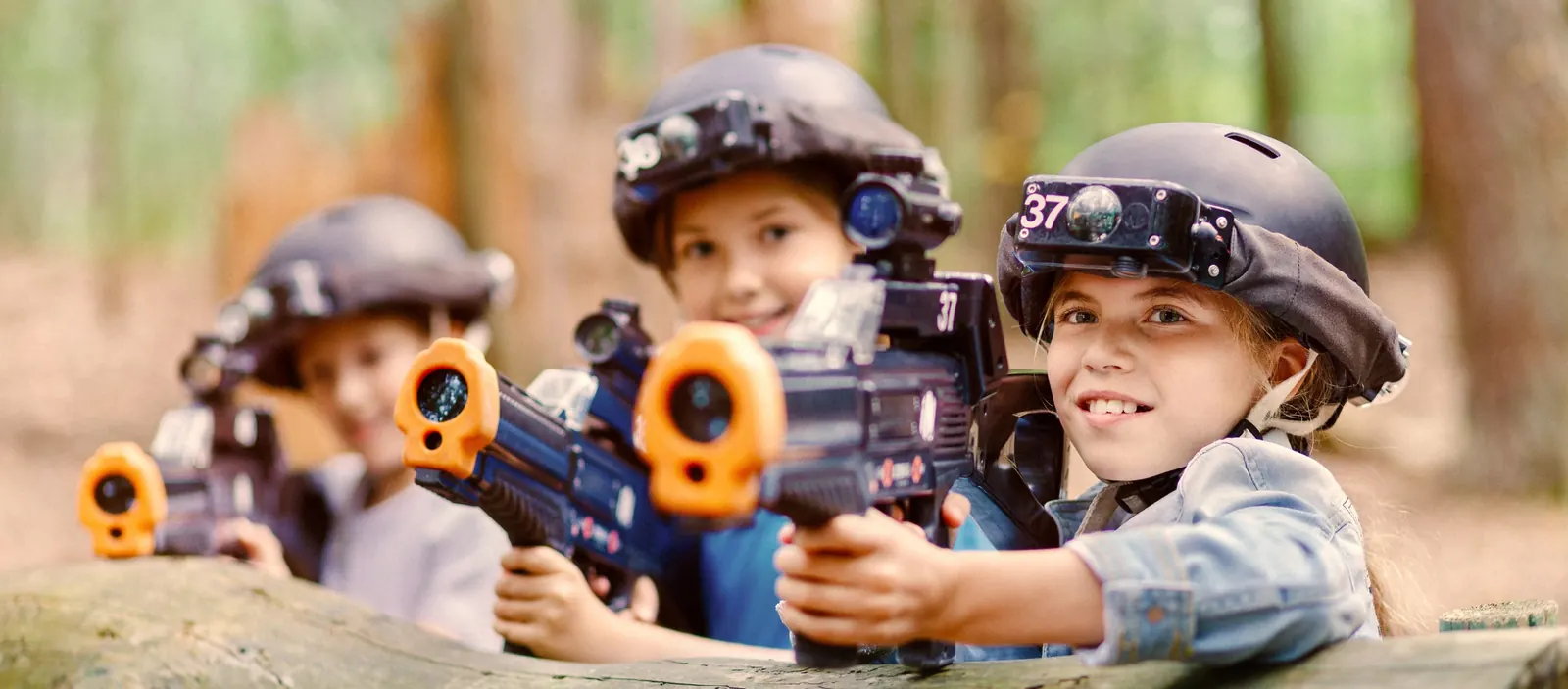 Enfants qui visent avec leurs lanceurs de laser game en forêt